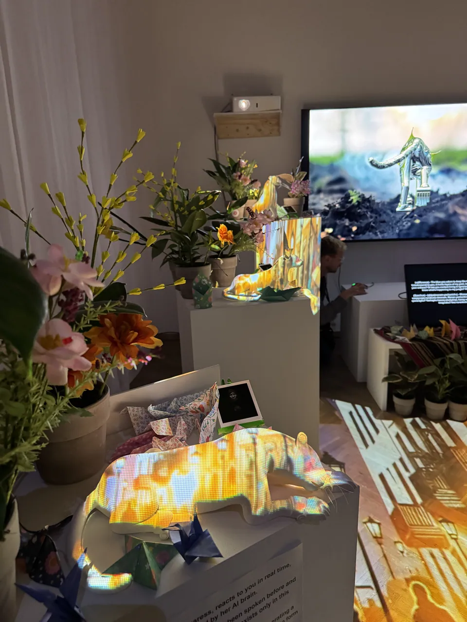 Flowers and a glowing jaguar sculpture on a plinth, with a screen behind.