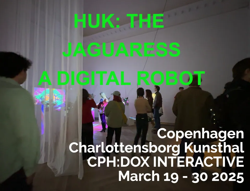 Visitors among projections in a white gallery. Green letters: Huk: The Jaguaress, a digital robot.