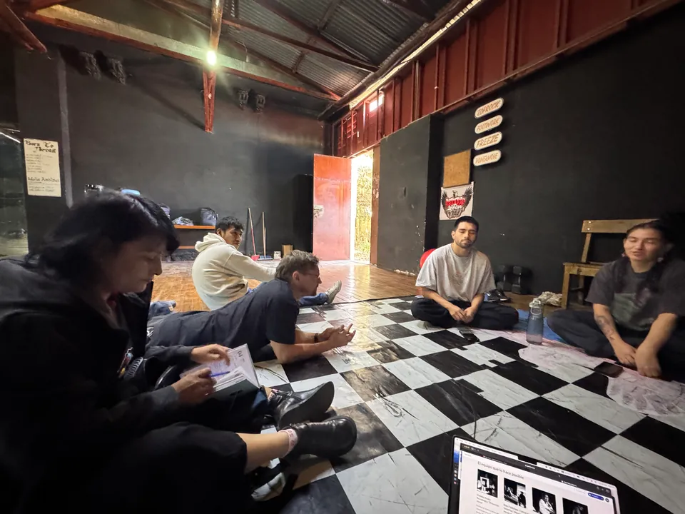Seen from one side, the circle of the first meeting on the checkered floor, with a laptop in front.