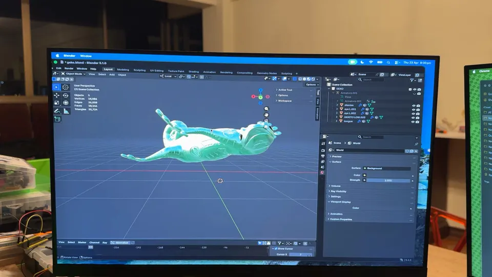 A monitor shows a turquoise gecko model lying on its back in Blender.